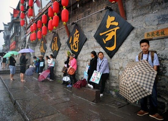 　4月29日上午11時(shí)20分，一些游客和古城當(dāng)?shù)氐木用穸阍谝粋€(gè)酒吧的屋檐下避雨。這些當(dāng)?shù)鼐用褚詾橛慰团恼罩\生，一場降雨讓他們的生意更加清淡。