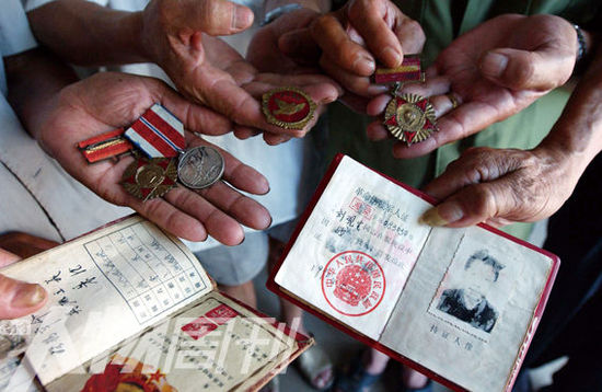幾位志愿軍老兵展示自己的立功證、傷殘軍人證與勛章