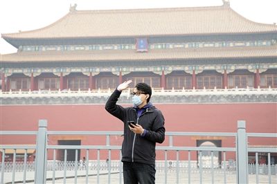 11月1日，北京大部分地區(qū)重度污染，一名游客戴著口罩在午門前揮手跟朋友打招呼。 實(shí)習(xí)生 王飛 攝