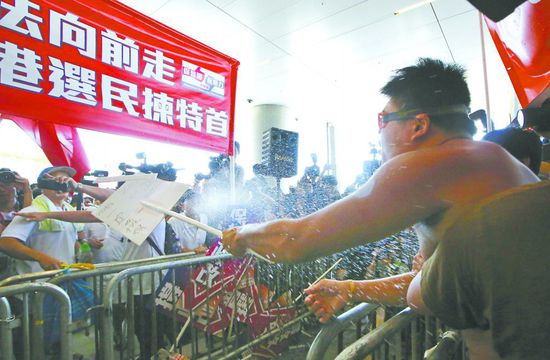17日，在香港立法會外，一名反對政改的男子向支持派人群投擲標(biāo)牌。