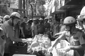 7月11日，瀏陽(yáng)市北正中路，執(zhí)法人員暫扣張海的水果。這是瀏陽(yáng)市城管局拍攝的執(zhí)法現(xiàn)場(chǎng)圖。