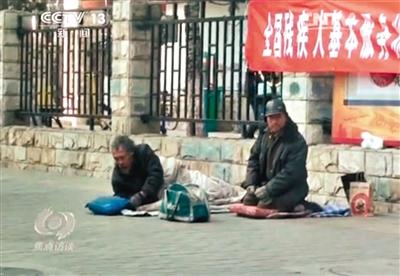 工人體育場(chǎng)北路，兩位乞討者路邊乞討，并輪流扮成“病人”（躺地者）。 央視截圖