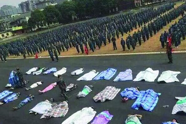 20多名女生躺在瀝青跑道上，身上嚴嚴實實地裹著棉被，接受太陽的照曬。