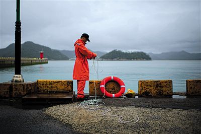 7月6日，韓國珍島，一名海岸警察在港口系救生圈。4月，客輪在珍島近海發(fā)生沉船事故后，仍有11人下落不明。