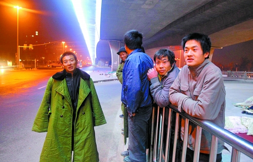 冬夜里，農(nóng)民工在橋下等著干活兒。