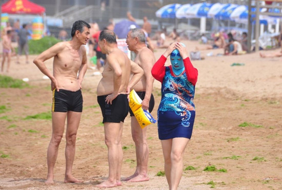 2013年7月3日，山東青島青島高溫來襲，“青島大媽”不懼滸苔，戴著“強盜面具”出現在海水浴場消暑降