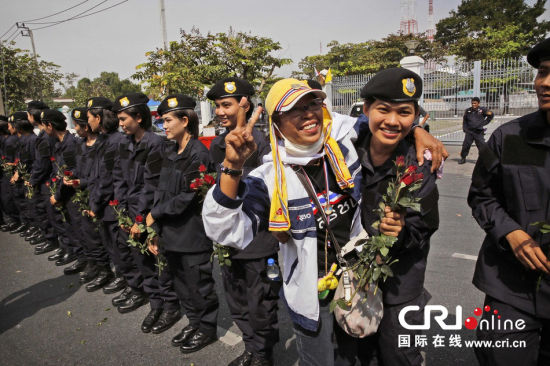 2013年12月03日,曼谷總理府與曼谷警署允許反政府示威民眾進入,雙方進入暫時“停戰(zhàn)”狀態(tài)迎接泰王生日。曼谷警察總署,女警們手持鮮花送給反政府示威民眾。圖片來源:Manish Swarup/東方IC