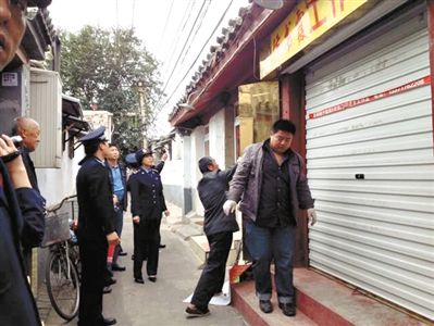 執(zhí)法人員拆除胡同里一家店面未經(jīng)審批的招牌。