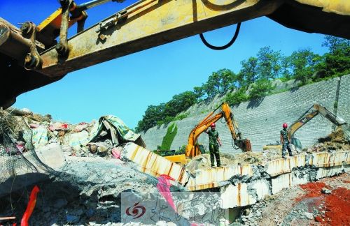 為確保道路盡早通車，工人師傅冒著烈日，指揮施工機械清理爆破現(xiàn)場