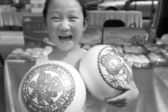在2013河南食品安全宣傳周活動現(xiàn)場，一個小女孩抱著參展的特色大饅頭樂開了花