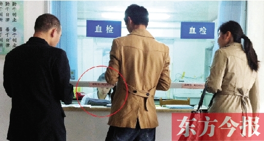 昨日，鄭州市二七區(qū)疾控中心辦證大廳，血檢窗口內一名女工作人員，邊接受辦證者咨詢邊看報紙