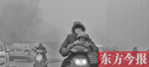 12月8日，鄭州市未來路上，一位市民帶著孩子在霧中騎行