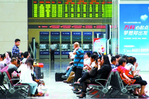 候車大廳溫度很高，一名乘客一手扇風、一手擦汗