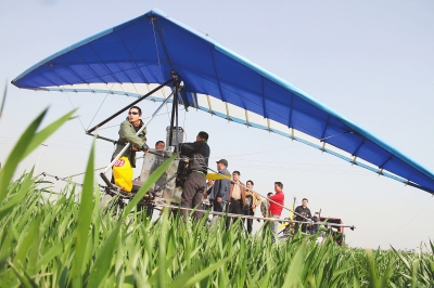 　　4月12日，在武陟縣北郭鄉(xiāng)韓余村，一架三角翼動(dòng)力滑翔機(jī)在對(duì)小麥進(jìn)行農(nóng)藥噴灑作業(yè)。為提升農(nóng)業(yè)生產(chǎn)的
