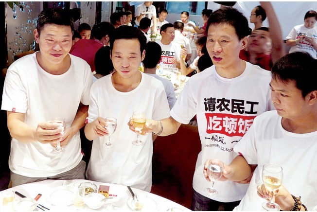 活動發(fā)起人張楠（右二）給農(nóng)民工敬酒。