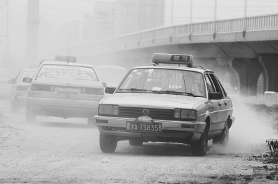 施工的道路上，車輛通過(guò)塵土飛揚(yáng)。