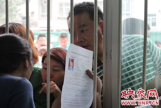 不少家長(zhǎng)擠在報(bào)名窗口前咨詢報(bào)名事宜。