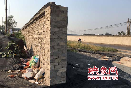 一墻之隔，一邊是道路，一邊是垃圾和荒草，市民質(zhì)疑其為遮羞墻。