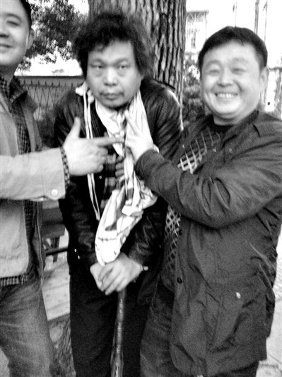 兩名接訪人員與患有癌癥的訪民段新德合影時，面帶笑容擺出勝利的手勢。