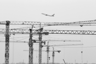 空中是起飛的飛機(jī)，下面是T2航站樓工地上林立的塔吊