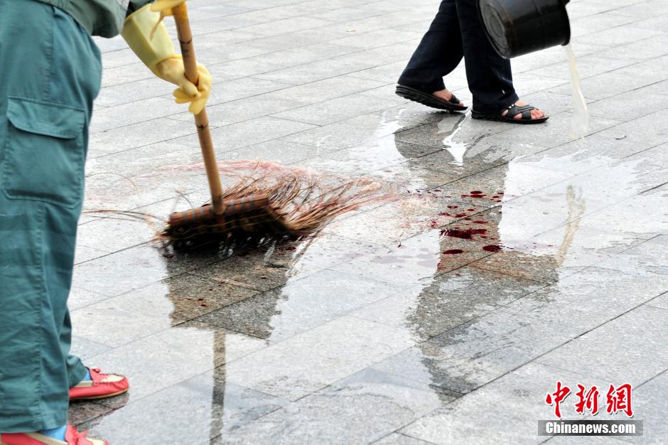 圖為環(huán)衛(wèi)工人在清理案發(fā)地點的血跡。