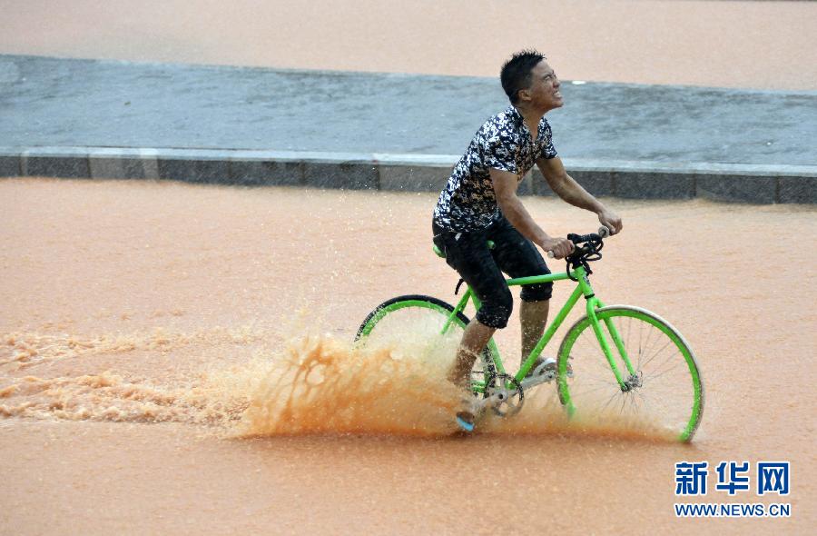5月11日，一名行人在深圳街頭冒雨騎行。