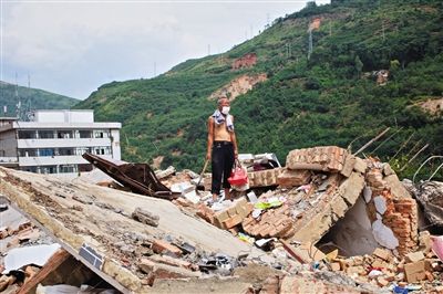 8月9日,龍頭山鎮(zhèn),一位老者在自家房屋廢墟上尋找家當。