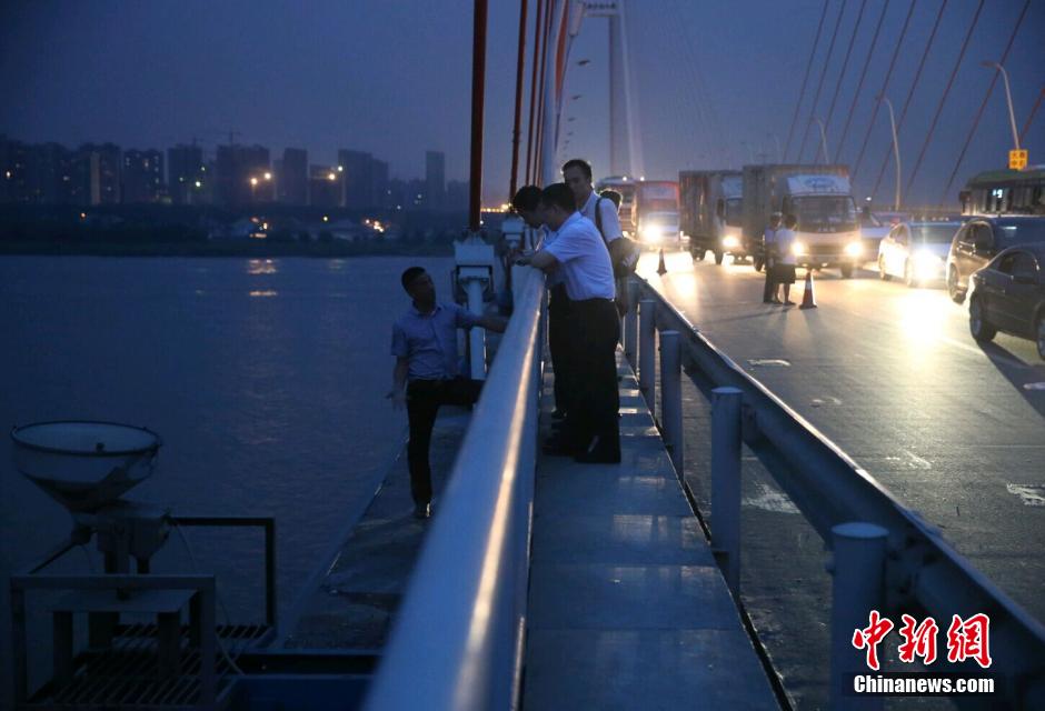 圖為武漢警方談判專(zhuān)家正在與翻爬至大橋外側(cè)護(hù)欄的劫持者談判。