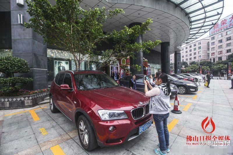一輛停在停車位上的寶馬轎車，被墜落的樹枝砸中，樹枝徑直插入車內，現場引發(fā)不少市民圍觀拍照。