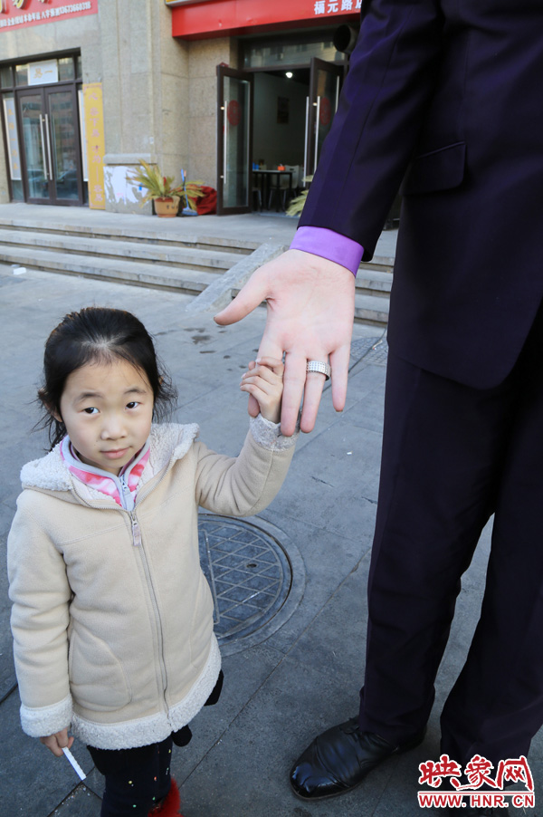 巨人“張歡”牽著一名漂亮的小女孩，兩人的手大小對比非常明顯。